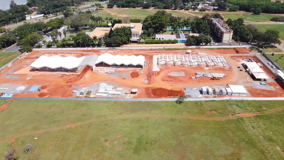 Vista aérea do conjunto de galpões em montagem, com as coberturas de telha branca já fechadas em parte da obra