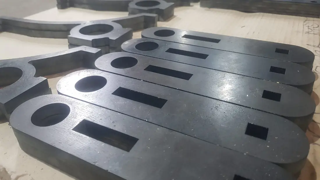 Peças de chapa cortadas e empilhadas sobre pallet, com rasgos alongados feitos no mesmo corte