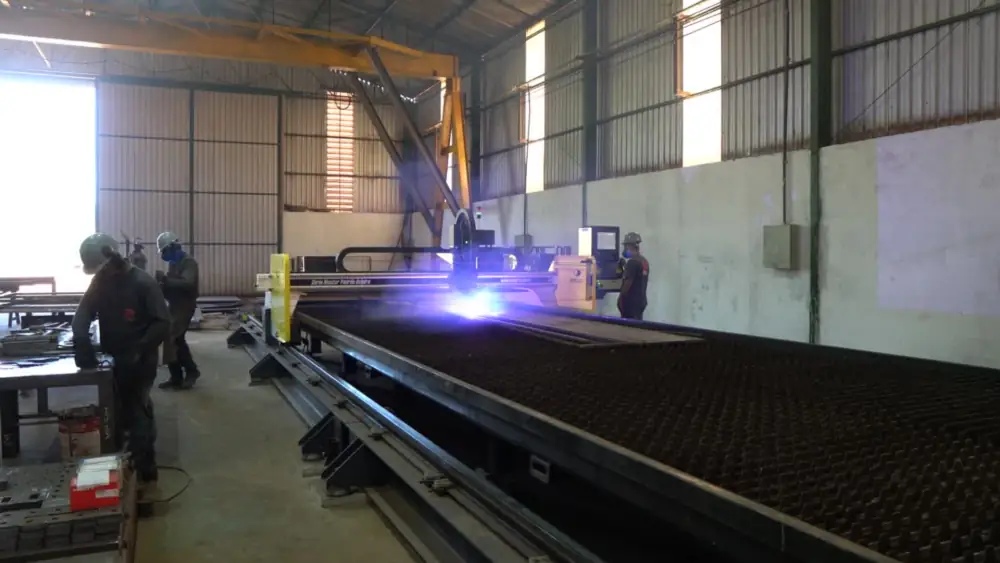Mesa de corte a plasma em operação dentro do galpão da MA Steel, com a chapa posicionada sobre a grelha